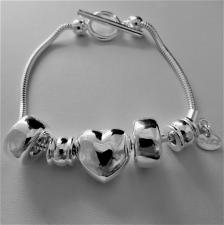 Bracciale in argento 925 charms scorrevoli. Fantasia cuore e barilotti. Chiusura a T-bar.